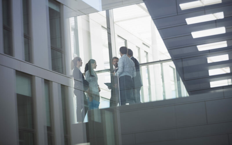 Group of businesspeople interacting in corridor of an office building